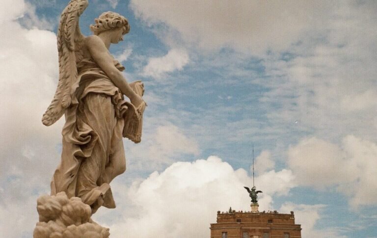 Statue on top of Castel Sant'Angelo in Rome against a blue sky